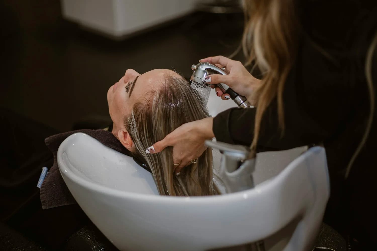 Client getting hair washed at salon wash station